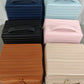 Six ribbed stripe makeup organizer cases stacked in navy, light blue, black, pink, brown and apricot