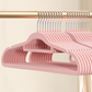 Pink flocked hangers in a row on a rail, close view of the slim shoulder shape