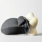 Deep gray back cushion supporting a pale mannequin torso, cover pushed up at the neck