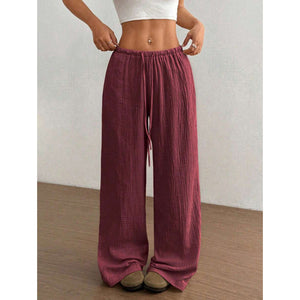 Woman wearing loose wide leg cotton trousers with a soft crinkle texture and tied waist