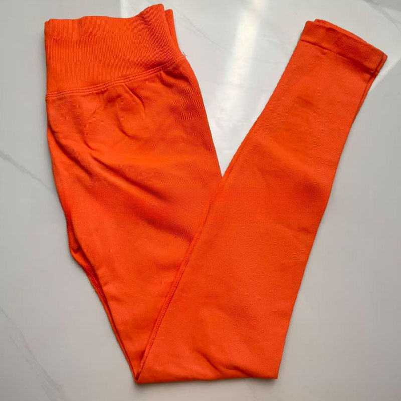 Coral red seamless yoga leggings folded flat, showing the tall ribbed waistband
