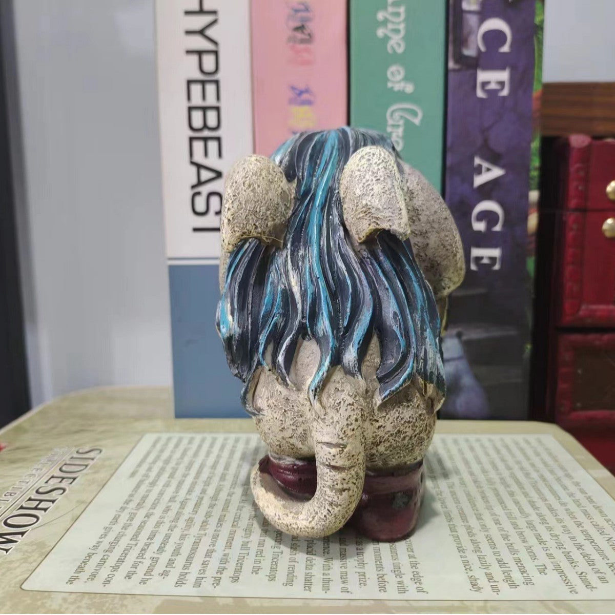 Back view of hand painted troll statue showing flowing teal and navy hair