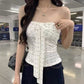 White floral tube top with bare shoulders and a long tie bow, styled with dark wide leg jeans