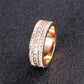 Rose gold tone band ring with three rows of clear stones lying on a dark textured surface