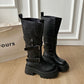 Black platform mid calf boots with two buckle straps standing on a wood floor