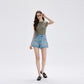 Model posing in light blue high waist denim shorts and dark loafers