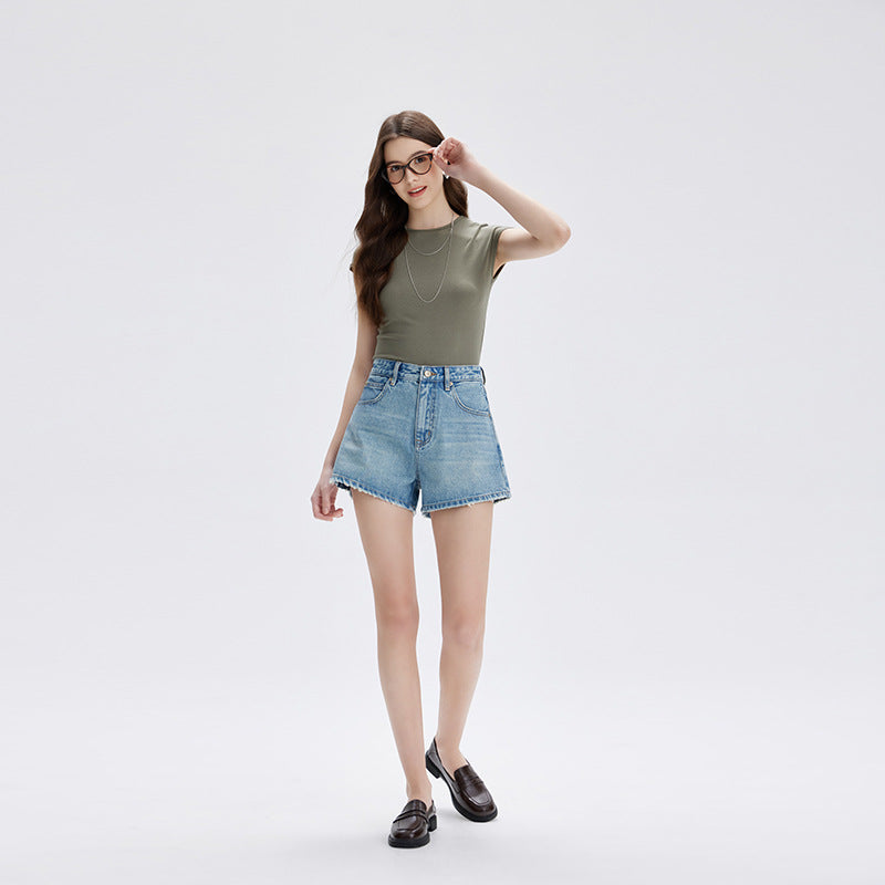 Model posing in light blue high waist denim shorts and dark loafers