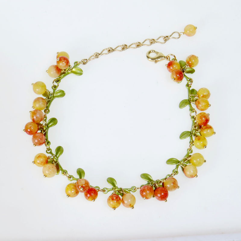 Seven color berry bead bracelet with green enamel leaves worn on a wrist