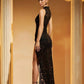 Back view of the sleeveless black dress with a ruched jersey hip panel and a lace skirt with a high slit by stone columns