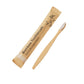 Single bamboo toothbrush with white soft bristles next to a kraft paper sleeve