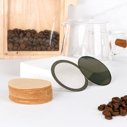 Natural paper filters and two stainless steel filter discs beside a glass coffee jug and beans