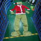 Flat lay of the costume: red coat with belt, green fur gloves, pants, foot covers, and hat with hood