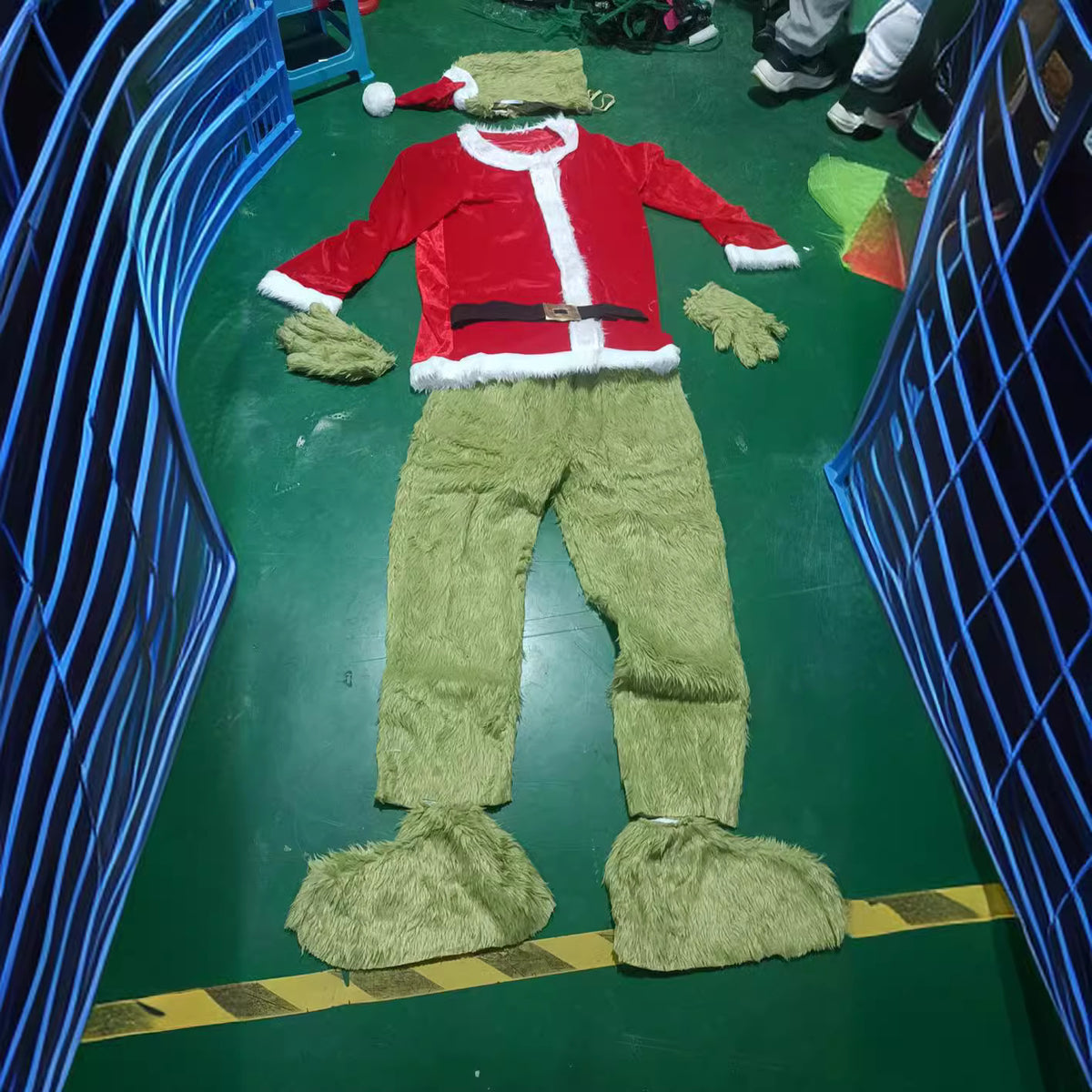 Flat lay of the costume: red coat with belt, green fur gloves, pants, foot covers, and hat with hood
