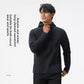 Man in a black half zip hooded sweatshirt with a zipped chest pocket, hand at the collar, vertical caption beside him