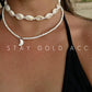 Cowrie shell choker worn with a separate white seed bead necklace and moon charm below it