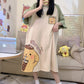 Woman in a living room in a cream nightgown with green sleeves, a chest patch and a big yellow dog print on the hem