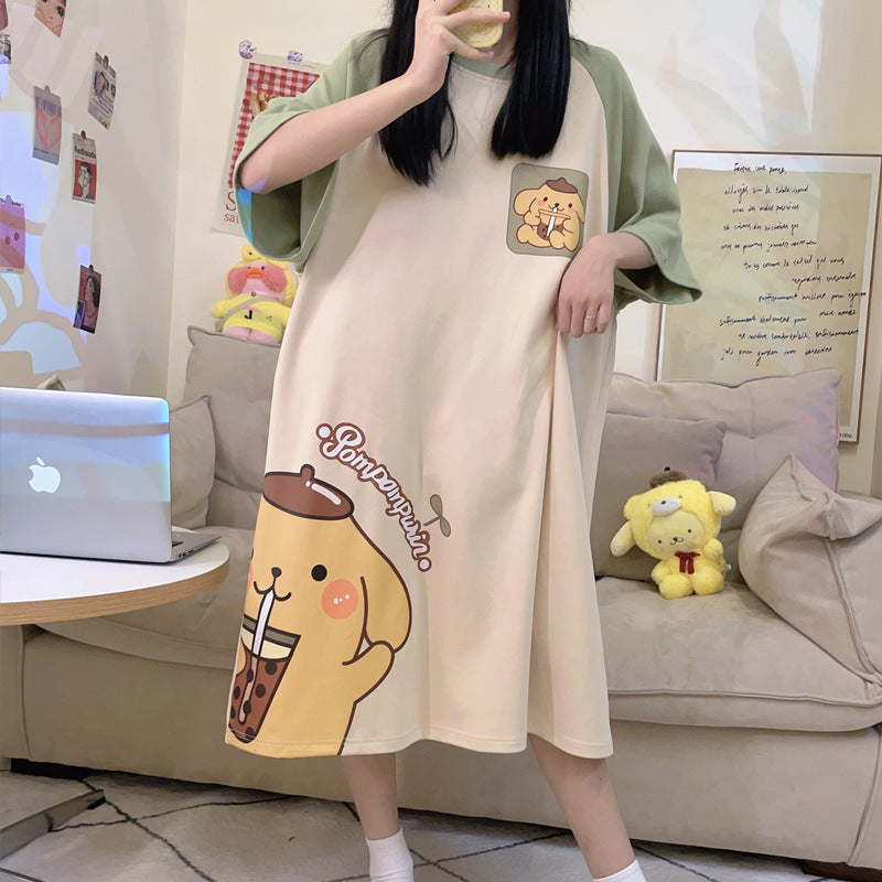 Woman in a living room in a cream nightgown with green sleeves, a chest patch and a big yellow dog print on the hem