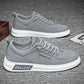Gray canvas low-top lace-up sneakers with white sole and side lettering on a gray carpet