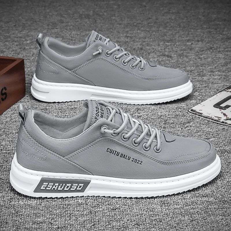 Gray canvas low-top lace-up sneakers with white sole and side lettering on a gray carpet