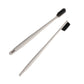 Two beige straw toothbrushes with charcoal bristles laid on a white background