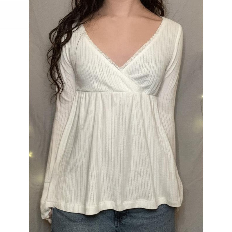 Woman in a white long sleeve crossover V neck babydoll top with lace edging, image for the White option in size L