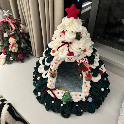 Finished dark green and white chenille tree shaped pet house with a red star and Santa and reindeer ornaments on a ledge