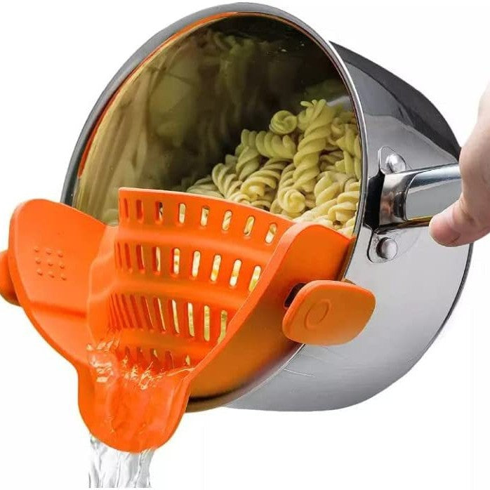 Orange silicone clip-on pot strainer, variant photo, clipped to a pot held by hand with water draining