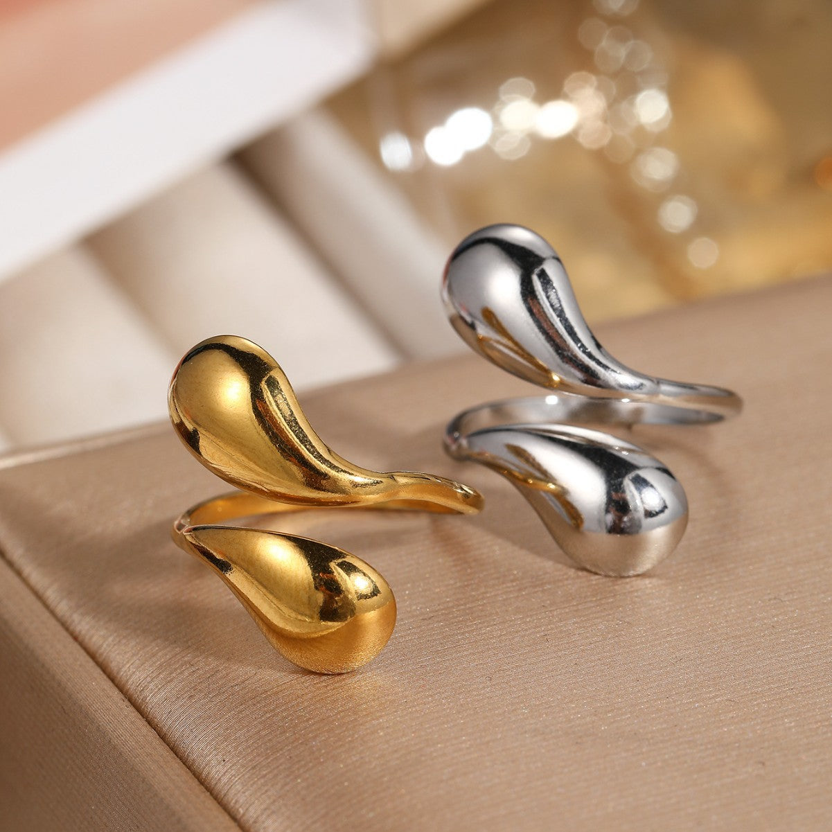 Gold and silver water drop bypass rings side by side showing both finishes