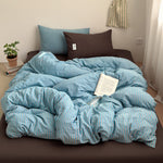 Blue and coral striped cotton quilt cover on a bed with a brown fitted sheet, brown pillowcase, a book and a plant