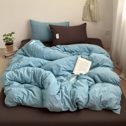 Blue and coral striped cotton quilt cover on a bed with a brown fitted sheet, brown pillowcase, a book and a plant