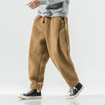 Man walking in camel brown plush harem pants with a drawstring waist, side view with high top sneakers