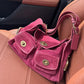 Raspberry pink suede shoulder bag with two twist lock front pockets resting on an orange leather seat