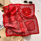 Red bandana paisley printed square scarf with a satin sheen and hemmed edges, shown displayed and knotted