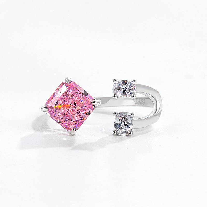 Radiant pink stone facing two clear oval accents across an open band stamped S925 near the opening
