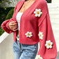 Cropped floral knit cardigan worn open over a plain top on a model