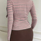 Back view of a pink and gray striped long sleeve top worn with a brown mini skirt