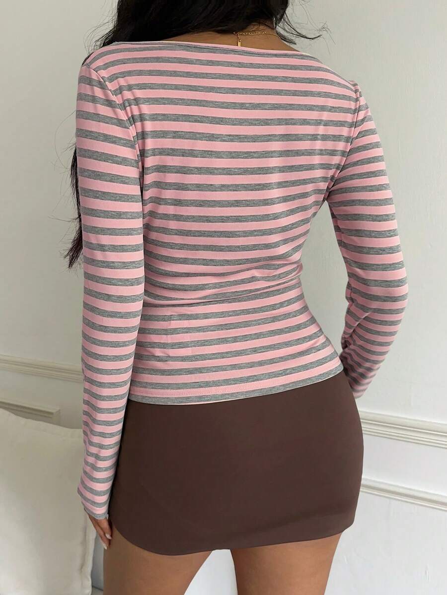 Back view of a pink and gray striped long sleeve top worn with a brown mini skirt