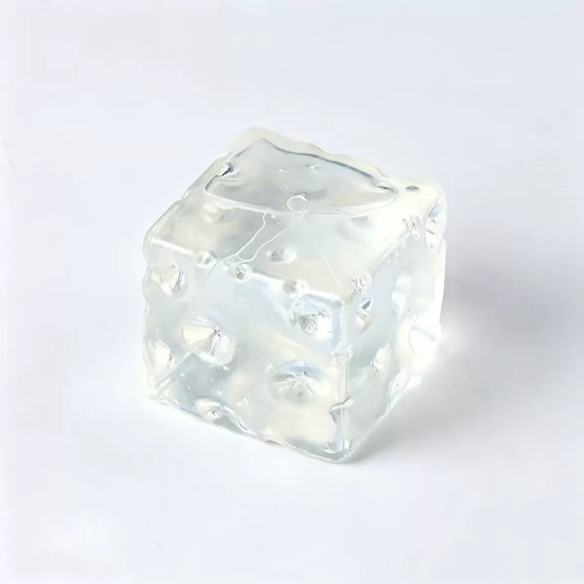 Translucent clear cheese cube squishy toy with moulded holes on a light background