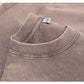 Close-up of a ribbed round collar with a woven label on a mauve washed cotton t-shirt, a color not listed