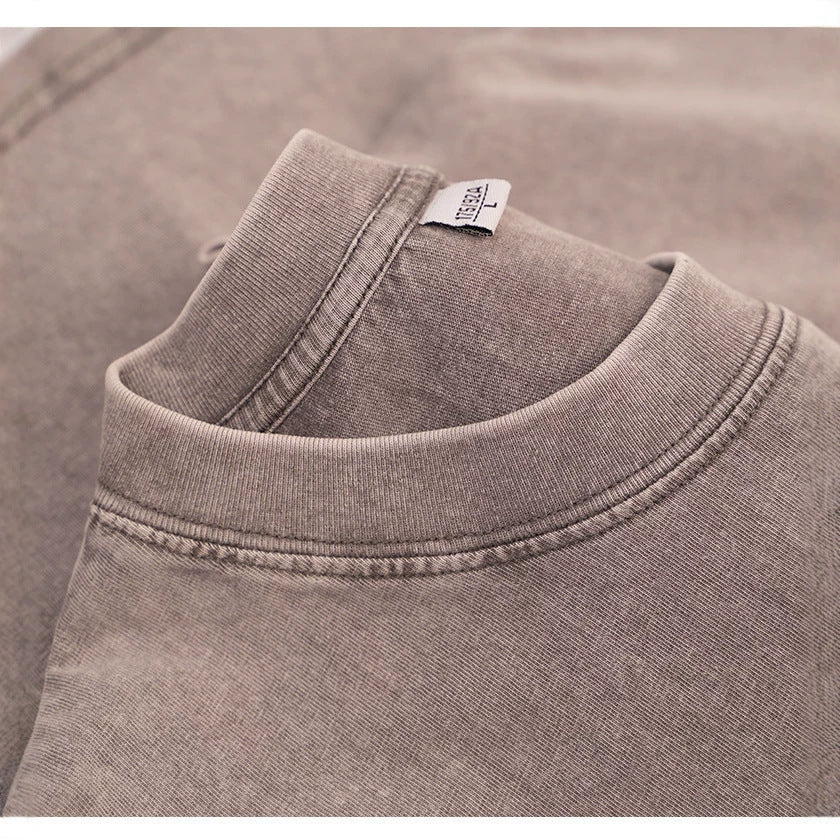 Close-up of a ribbed round collar with a woven label on a mauve washed cotton t-shirt, a color not listed