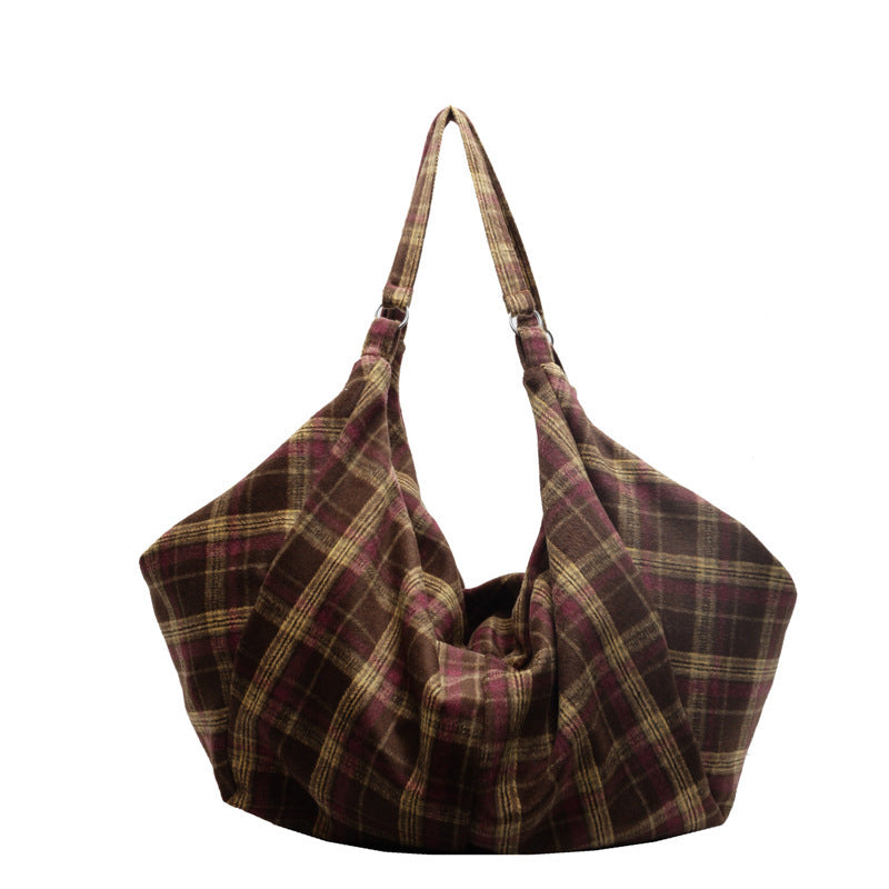 Dark brown woolen plaid shoulder tote bag with zip top closure standing on a surface