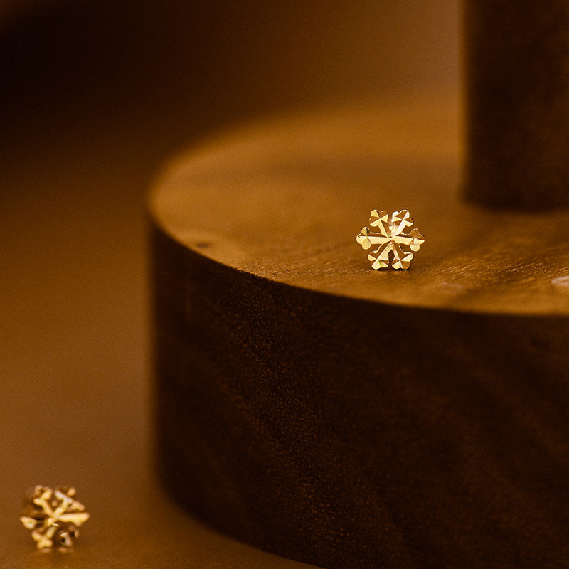 Angled view of the gold snowflake floral stud earrings showing the warm gold tone
