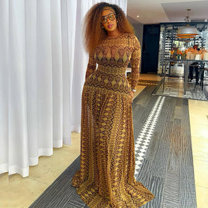 Woman in an amber and brown geometric print mesh maxi dress with long sleeves, front view
