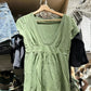 Green short-sleeve deep V-neck top with an empire waist band and gathered hem on a hanger