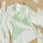Mint green ribbed halter triangle bikini set laid flat on a white shirt with beach props