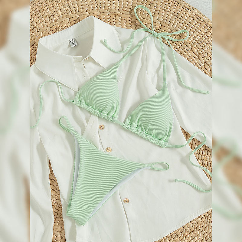 Mint green ribbed halter triangle bikini set laid flat on a white shirt with beach props