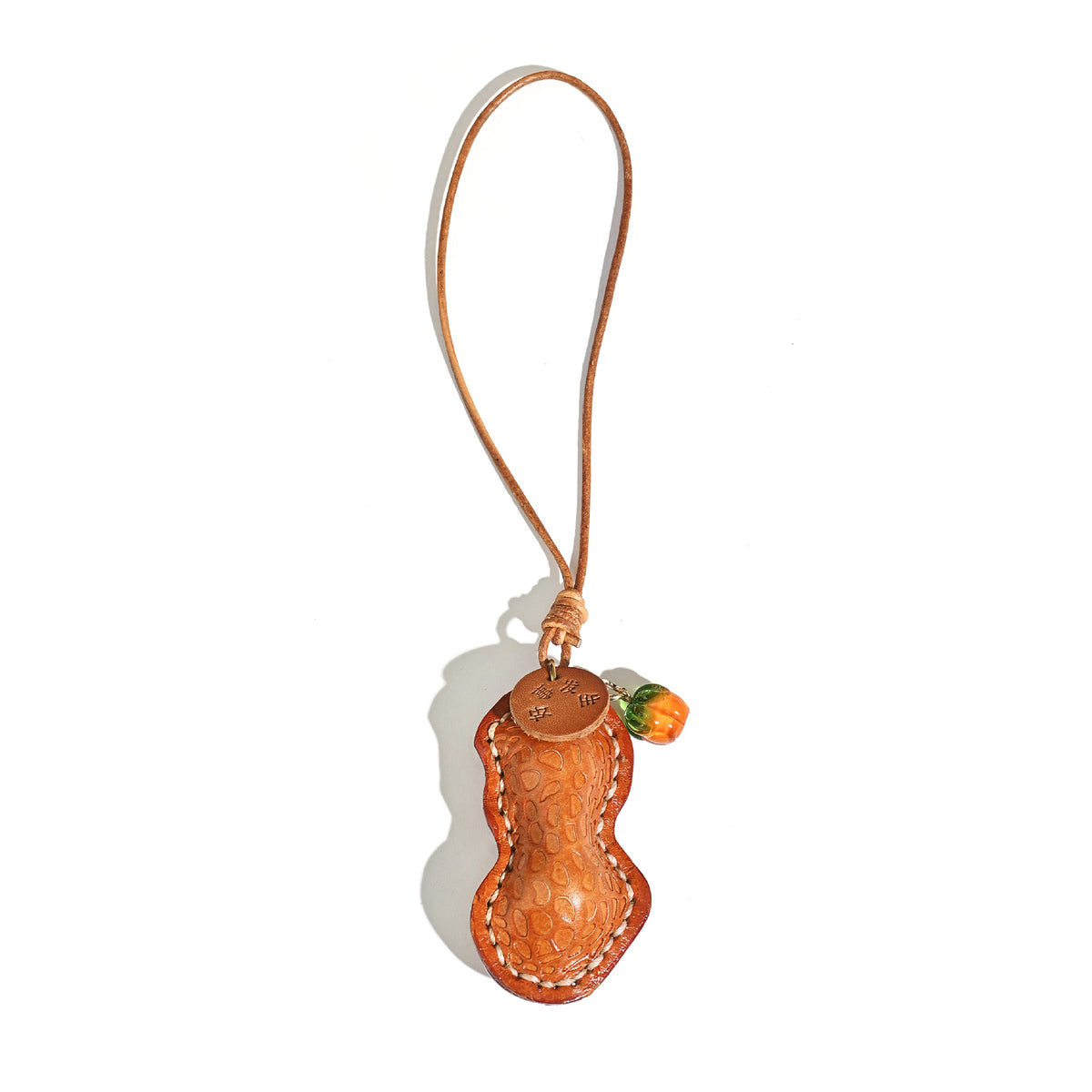 Tan orange peanut shaped leather pendant with cord loop and orange glass bead on a white background