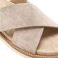 Close view of a light taupe suede crossed strap over a stitched suede footbed and the cream sole edge