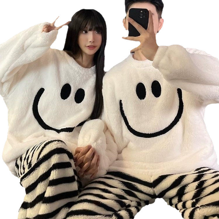 Couple in white fleece smiley face pajama tops and black cream striped trousers on a white background