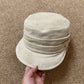 Gold heart charm on the side of a vegan suede flat cap, close view